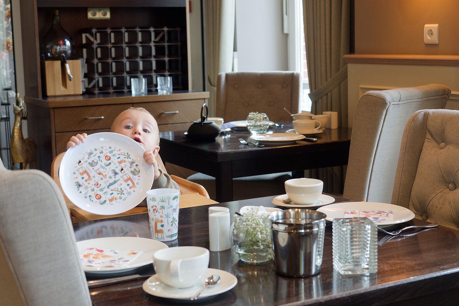 Kleines Kind sitzt im Hochstuhl und frühstückt im Hotel von Euch in Meppen